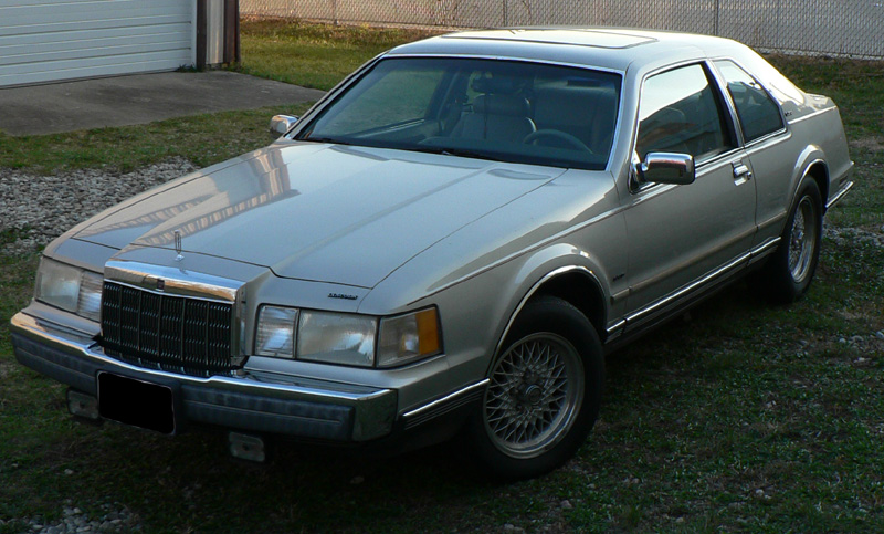 Silver 1990 Lincoln Mark VII coupe parked on grass, front quarter view