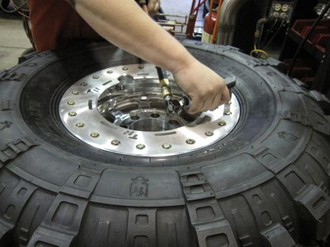 1992 Ford Bronco - Inflating a large off-road tire with a polished metal wheel. Supermotors.net logo visible.