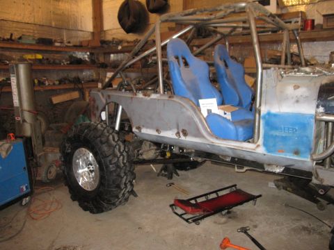 1992 Ford Bronco - This custom off-road vehicle is undergoing modifications, a prominent roll cage and bright blue racing seats.