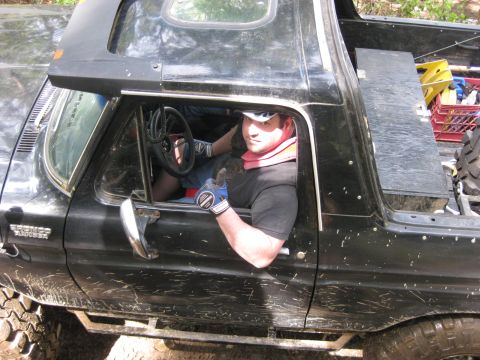 1979 Ford Bronco - A driver sits in a muddy black 1978 Ford Bronco, wearing a neck brace and giving a thumbs up.