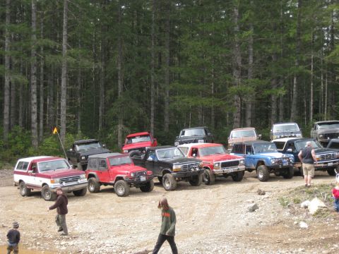 1979 Ford Bronco - A gathering of off-road vehicles in a wooded area, with several people present.