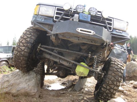 1979 Ford Bronco - This heavily modified SUV, likely from the early 1980s, is shown tackling a challenging off-road course.