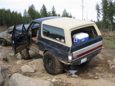 1979 Ford Bronco - Ford Bronco navigating rocky terrain with its door open, another vehicle in the background.