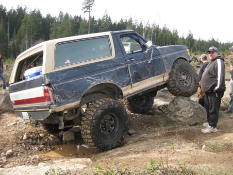1979 Ford Bronco - A modified Ford Bronco navigates a rocky obstacle on an off-road trail.