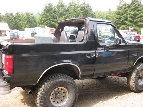1979 Ford Bronco - Side view of a black SUV with a removable roof and off-road tires.
