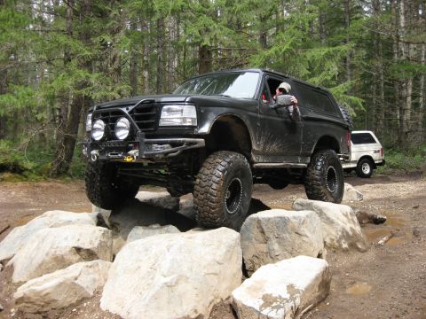 1979 Ford Bronco - This black Ford Bronco navigates a rocky trail, with another white SUV visible in the background.