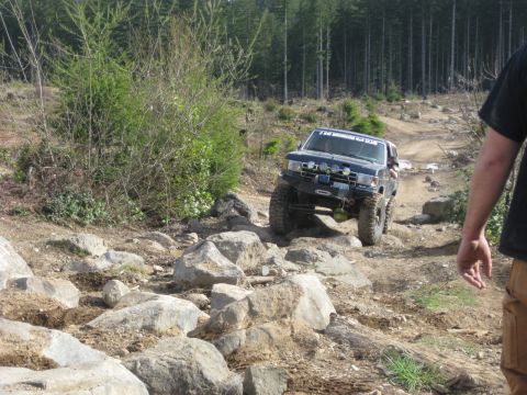1979 Ford Bronco - An off-road SUV navigates a challenging rocky trail in a wooded area.