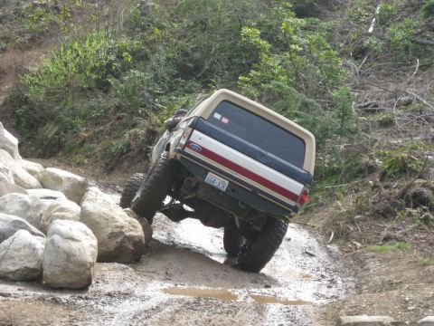 1979 Ford Bronco - This Ford Bronco is navigating a challenging off-road course with large rocks and mud.