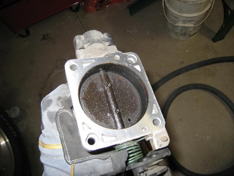 Dirty throttle body being held by a gloved hand