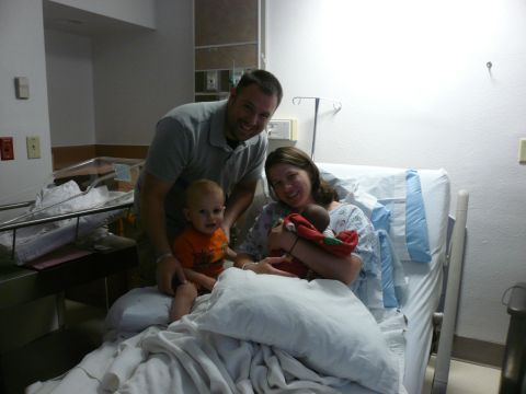 1996 Ford Probe - A family celebrates the arrival of a new baby in a hospital room, with an older sibling present.