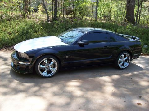 2007 Ford Mustang - A black Ford Mustang GT is parked on a concrete driveway with trees in the background.