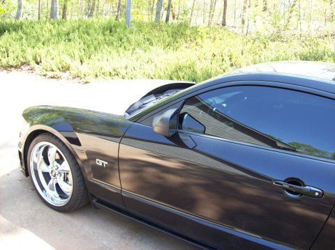 2007 Ford Mustang - Side view of a black 2007 Ford Mustang GT with chrome wheels and a GT badge on the fender.