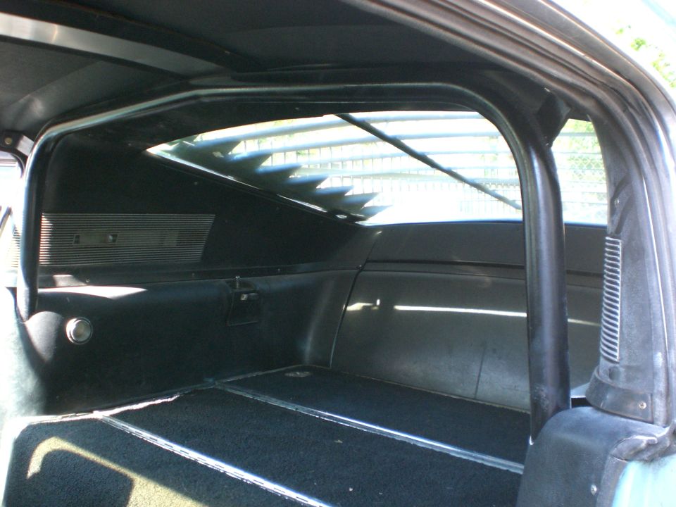 Rear cargo interior of an SUV showing roll bar and louvered rear window