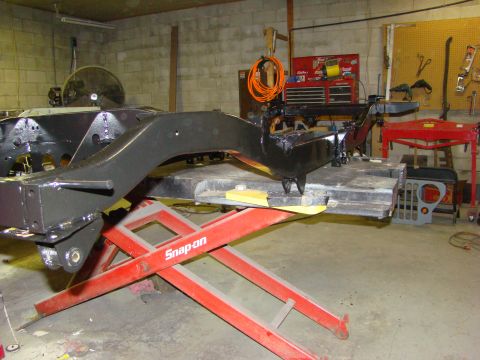 1948 Jeep Wrangler - The vehicle's frame is being worked on in a garage setting, with tools and equipment around.