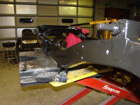 1948 Jeep Wrangler - A vehicle frame is shown undergoing work on a lift, with a lawn tractor visible in the background.