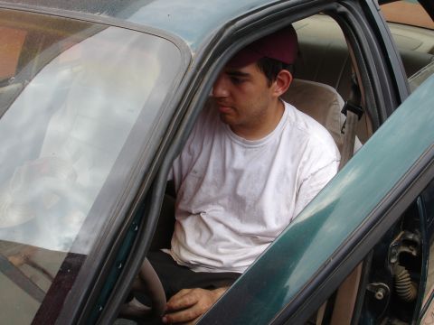 1995 Ford Taurus - A man sits inside the driver's side of a green vehicle, looking away from the camera.