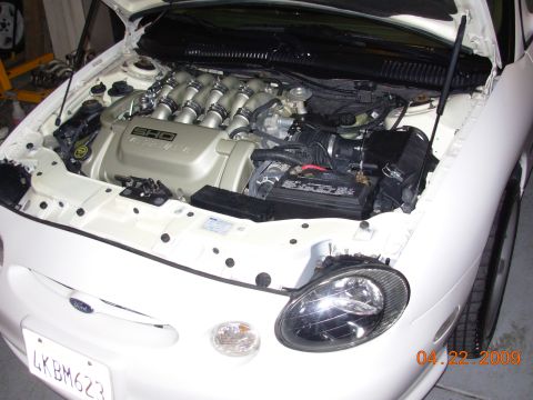 1995 Ford Taurus - The engine bay of a white Ford Taurus SHO, its distinctive V8 engine cover and intake system.