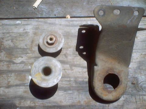 1976 Ford F-100 - Truck suspension parts including rubber bushings and a metal bracket are laid out on a wooden surface.