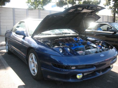 1995 Ford Probe - A blue 1995 Ford Probe is parked with its hood open, revealing a modified engine bay.