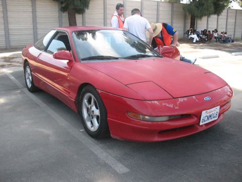 1995 Ford Probe - A red 1995 Ford Probe is parked in a lot, showing its distinctive pop-up headlights and California license plate.