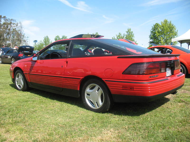 Red first-generation Ford Probe Turbo, rear three-quarter view on a car show field