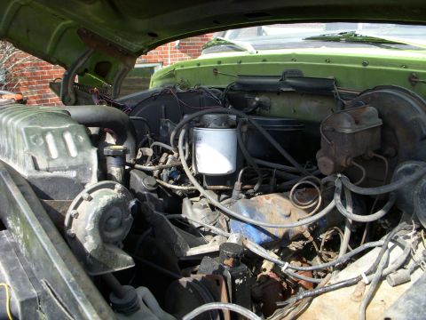 1974 Ford F-350 - The engine bay of a green 1974 Ford F-350 shows a V8 engine, radiator, and brake fluid reservoir.