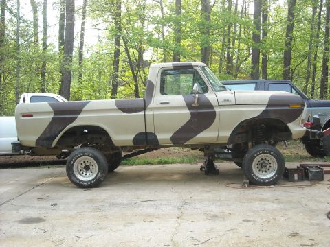 1979 Ford F-150 - This lifted Ford F-150 features a unique camouflage paint job and appears to be undergoing maintenance.