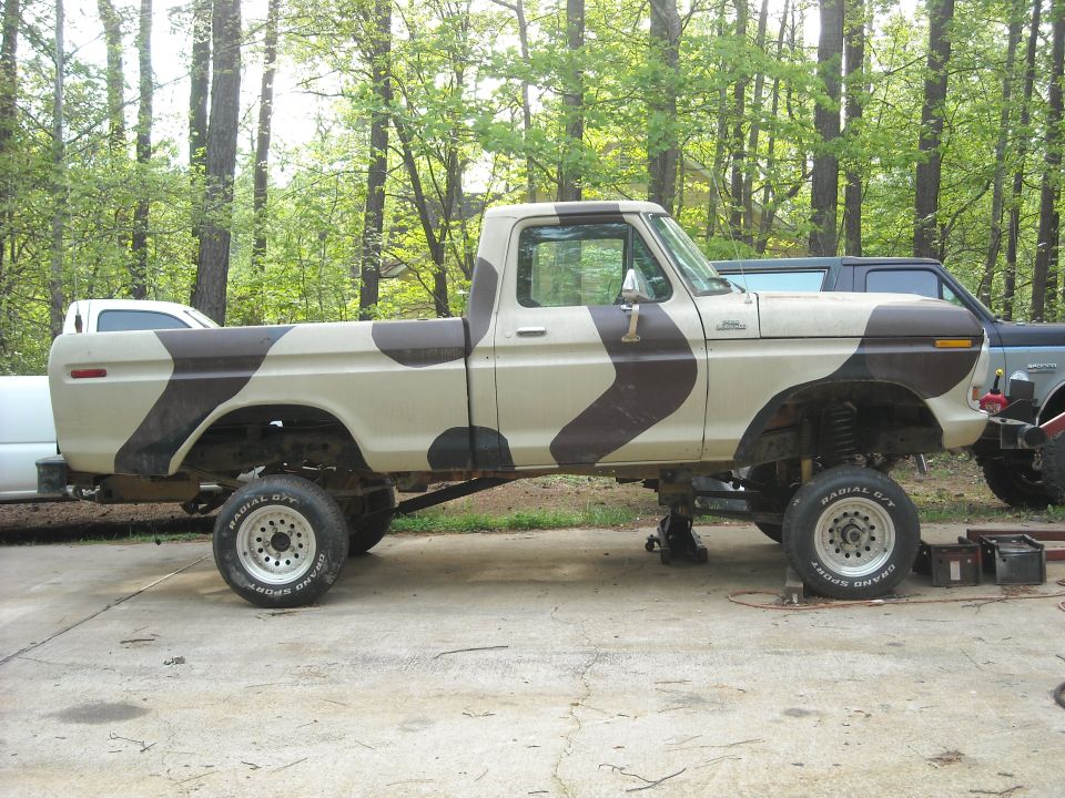 Side view of a 1979 Ford F-150 with camouflage paint, lifted on jacks