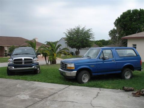 1992 Ford Bronco - A blue 1992 Ford Bronco and a dark blue Dodge Ram pickup truck are parked in a residential driveway.