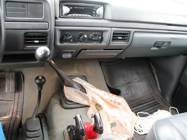 Interior shot of a truck's dashboard and center console, showing two gear shifters for a manual transmission