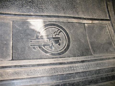 1992 Ford Bronco - Close-up of a vehicle's interior floor mat an embossed circular logo with a car silhouette.