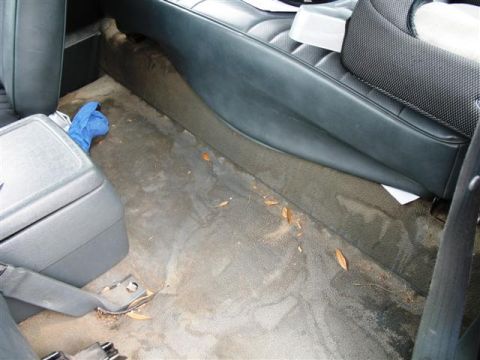 1992 Ford Bronco - The interior of a vehicle shows a dirty floor with debris and a blue cloth.