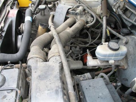1992 Ford Bronco - Close-up view of a vehicle's engine bay, showing various components and hoses.