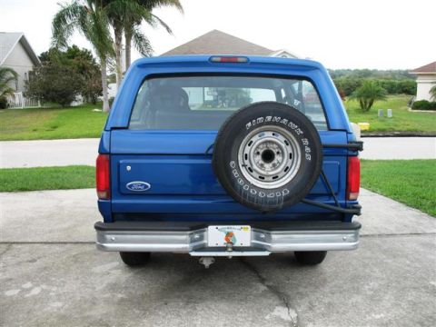 1992 Ford Bronco - Rear view of a blue 1992 Ford Bronco, a spare tire mounted on the tailgate and a visible license plate.