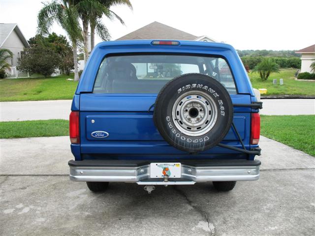 Blue Ford Bronco rear view with swing-out spare tire carrier on driveway