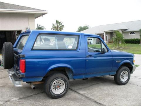 1992 Ford Bronco - Side view of a blue 1992 Ford Bronco, parked in front of a residential house.