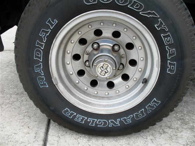 Close-up of a Goodyear Wrangler radial tire on a silver multi-hole rim with a chrome hubcap