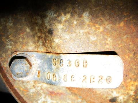 1992 Ford Bronco - A close-up view of a VIN plate with stamped characters, attached to a rusty surface.