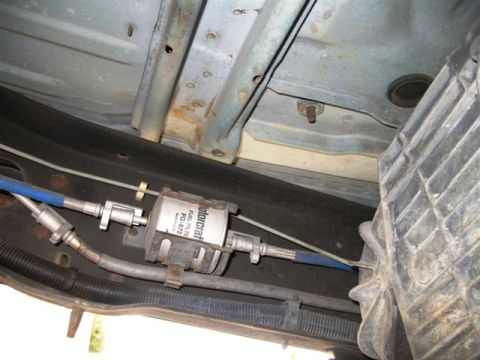 1992 Ford Bronco - Underneath a vehicle, a Motorcraft fuel filter labeled FG-872 is visible, connected to blue fuel lines. The filter is mounted to the vehicl…