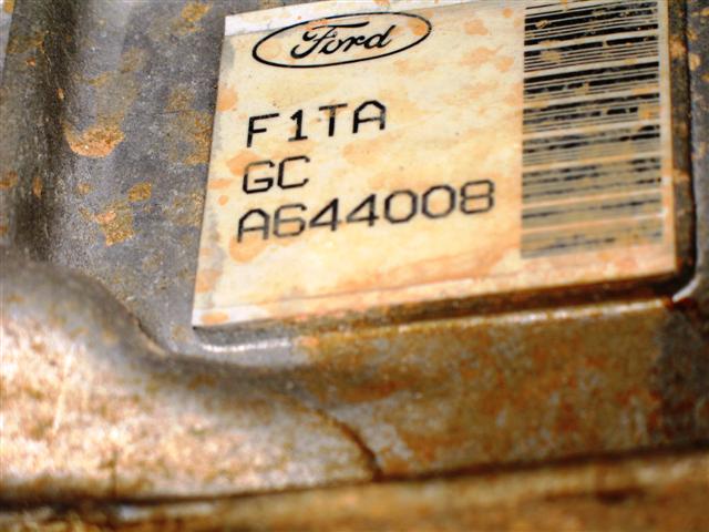 Ford barcode label F1TA GC A644008 on a rusty cast metal housing