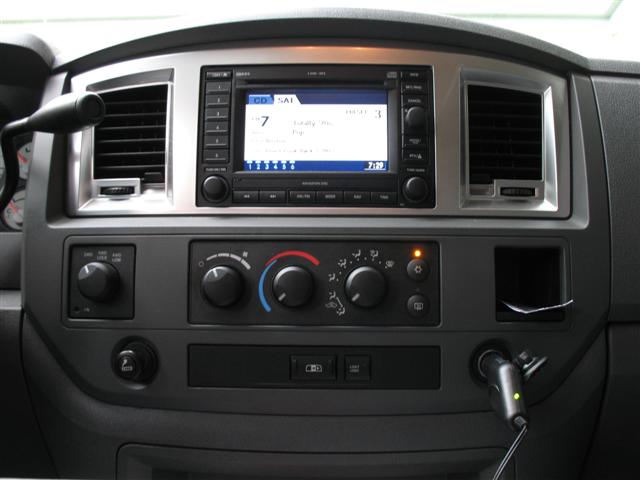 Dodge Ram center dash with navigation radio, HVAC knobs, 4WD selector, and device plugged into power outlet