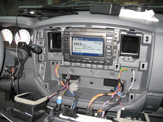 Truck dashboard disassembled showing factory radio tuned to 102.5 with exposed wiring harnesses below