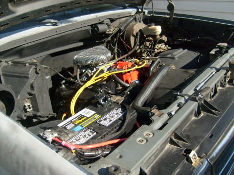 1987 Ford Bronco - The engine compartment shows a battery, air filter, and various hoses and wires. Tools are present on the radiator support.