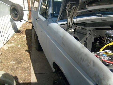1987 Ford Bronco - This 1980s Ford Bronco is shown from a 3/4 front angle with its hood up and a spare tire on the back.
