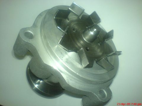 1992 Ford Crown Victoria - This is a close-up, overhead view of a metal water pump impeller and housing. The impeller has six angled blades and is mounted on a centra…