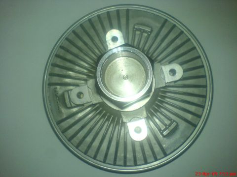 1992 Ford Crown Victoria - A close-up, overhead view of a metal fan clutch assembly. The part has a central hub with radiating fins and mounting points, and a serial…