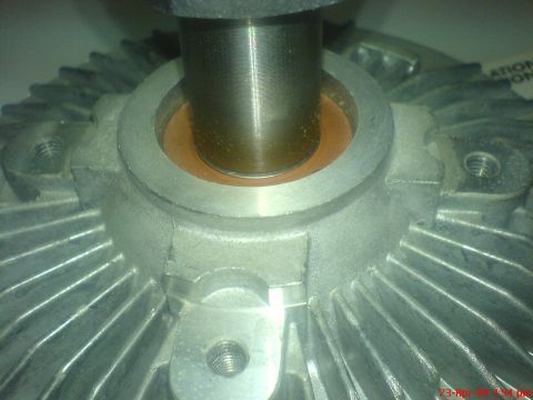 1992 Ford Crown Victoria - Extreme close-up of a new thermal fan clutch, looking down its threaded steel drive hub into the copper-colored bearing bore of the finned…