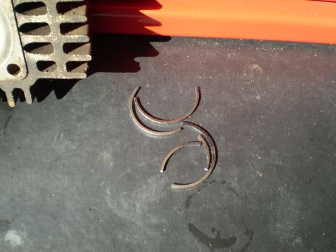 1981 Garelli Rally Sport - Several broken piston rings and a finned engine component are shown on a dark surface.
