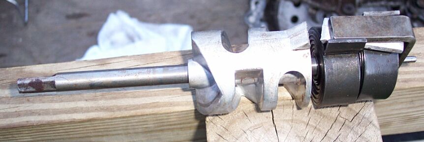 Metal shaft with cast aluminum housing and gear resting on a wooden board