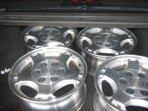1996 Ford Thunderbird - Four Chevrolet alloy wheels are stored in the trunk of a vehicle.